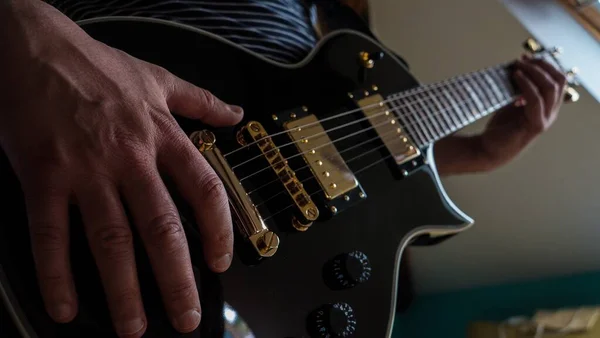 Close Uma Pessoa Tocando Uma Guitarra Elétrica Preta Sob Luzes — Fotografia de Stock