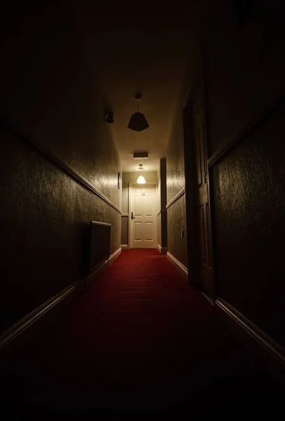 Вертикальний Знімок Вузького Темного Коридору Червоними Килимами Білими Дверима Кінці — стокове фото