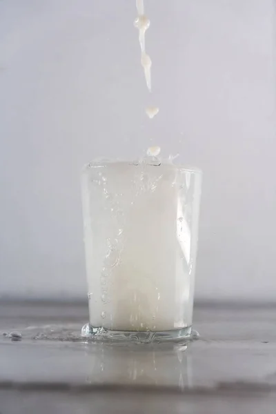 倒入玻璃杯中的白色液体的垂直镜头 — 图库照片
