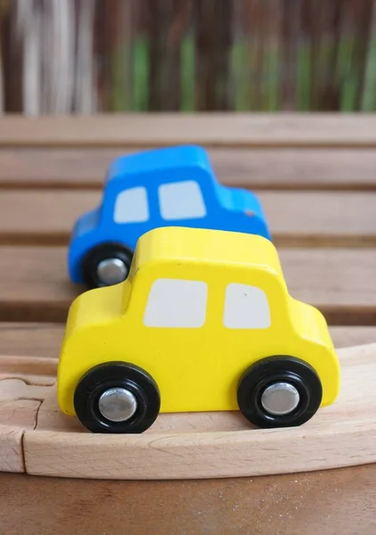 Tahta Bir Yüzey Üzerinde Iki Mavi Sarı Oyuncak Arabanın Dikey — Stok fotoğraf