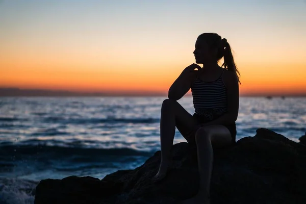 Silhouette Young Female Sitting Rock Ocean Staring Breathtaking Sunset — Stock Photo, Image
