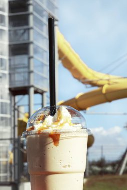 A closeup vertical shot of an ice cream smoothy on an aquapark background clipart
