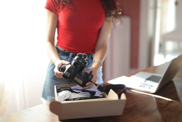 Μια Γυναίκα Που Κρατάει Μια Κάμερα Ένα Σημειωματάριο Στο Τραπέζι — Φωτογραφία Αρχείου