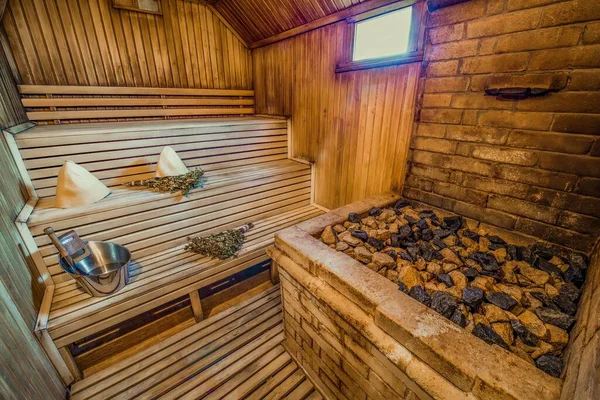 A beautiful sauna room design with a wooden bench and sauna rocks