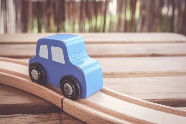 Zbliżenie Niebieskiego Drewnianego Samochodu Zabawki Torach Pod Światłami Rozmytym Tłem — Zdjęcie stockowe