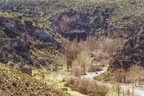 由岩石悬崖和美丽的绿地环绕的弯弯曲曲的道路的高角镜头 — 图库照片