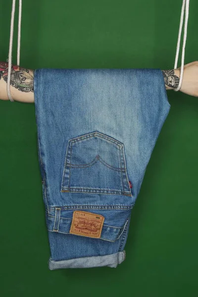 Jeans Pendurados Braço Tatuado Isolado Fundo Verde — Fotografia de Stock