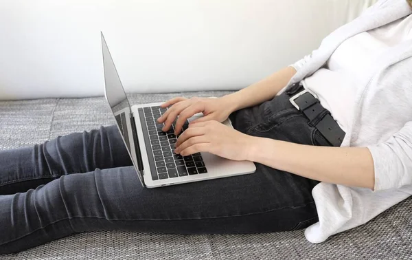 Piękne Ujęcie Kobiety Leżącej Laptopem Szarej Kanapie Białą Ścianą Jako — Zdjęcie stockowe