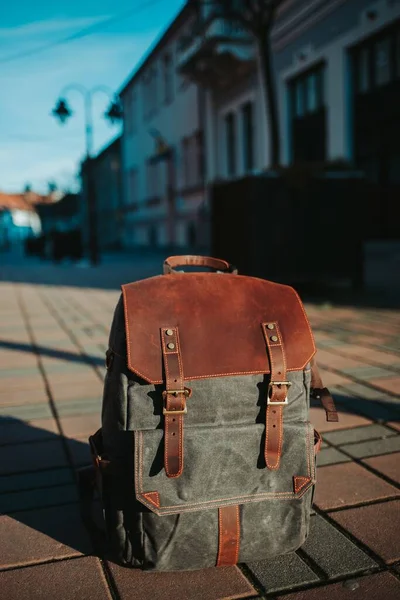 一个灰色和棕色背包的垂直特写镜头在街上的地面上 — 图库照片