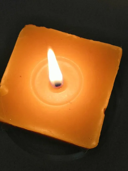 一个带有深色背景概念的方形橙色蜡烛的垂直特写镜头 — 图库照片