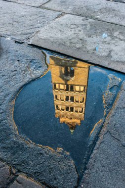 Scenic view of Pistoia Cathedral (Cattedrale di San Zeno) bell tower reflected in a puddle, Tuscany, Italy clipart