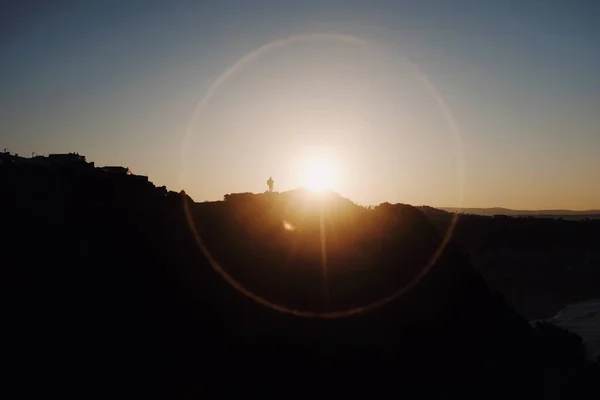 日没時に岩の多い丘の上を歩く人の低角度ショット — ストック写真
