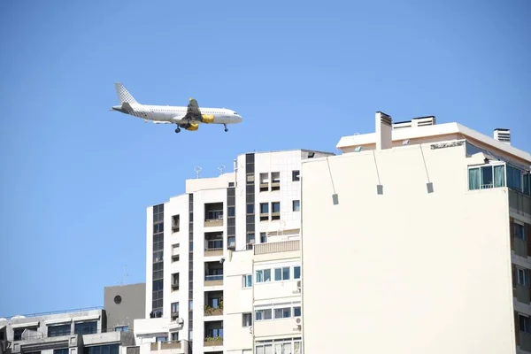 在阳光明媚的日子里 一架飞机在蔚蓝的天空中飞越大楼的景象 — 图库照片