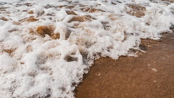 与沙滩相交的泡沫浪高角度特写 — 图库照片