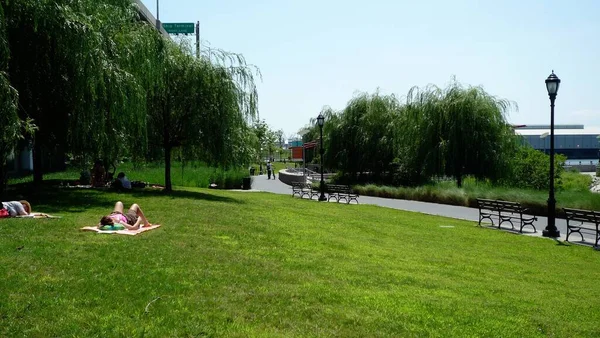 一群人在阳光灿烂的蓝天下在城市公园的草坪上休息 — 图库照片