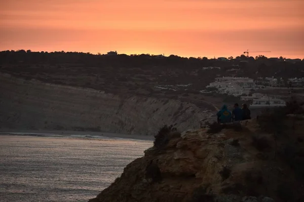 Τρία Άτομα Κάθονται Κοντά Στην Παραλία Κατά Διάρκεια Ενός Ηλιοβασιλέματος — Φωτογραφία Αρχείου