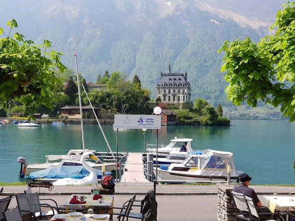 スイスのラウターブルネンを背景に家のある湖に係留されたボートを持つドックの景色 — ストック写真