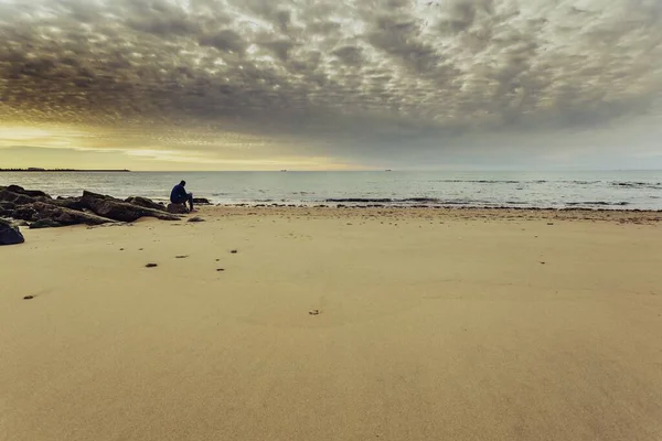 Deniz Kıyısındaki Bir Kayanın Üzerinde Oturan Bir Adam Gün Batımında — Stok fotoğraf