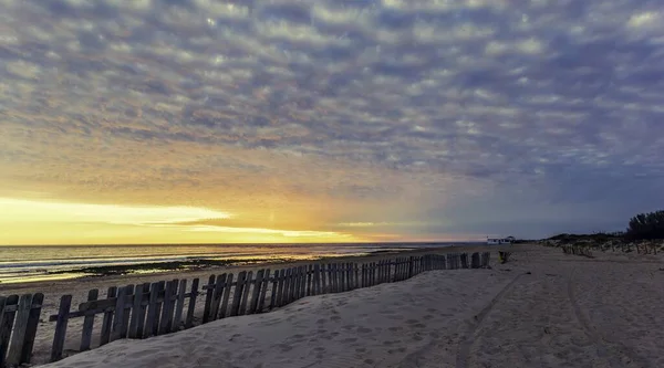 曇り空の日にビーチから撮影された波状の海の美しい夕日の景色 — ストック写真