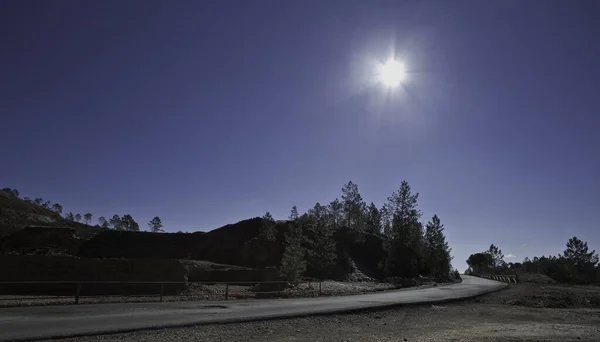 輝く太陽の下で山や緑に対して新しく建てられた道路の美しい写真 — ストック写真