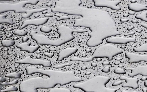 Eine Nahaufnahme Von Wassertropfen Auf Einer Grauen Glatten Oberfläche — Stockfoto