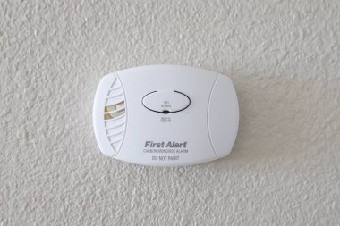 SPARKS, NEVADA, UNITED STATES - Apr 27, 2020: A First Alert carbon monoxide detector hangs in a home wall. clipart