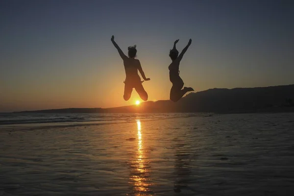 Silhouette Due Donne Che Saltano Sulla Riva Della Spiaggia Durante — Foto Stock