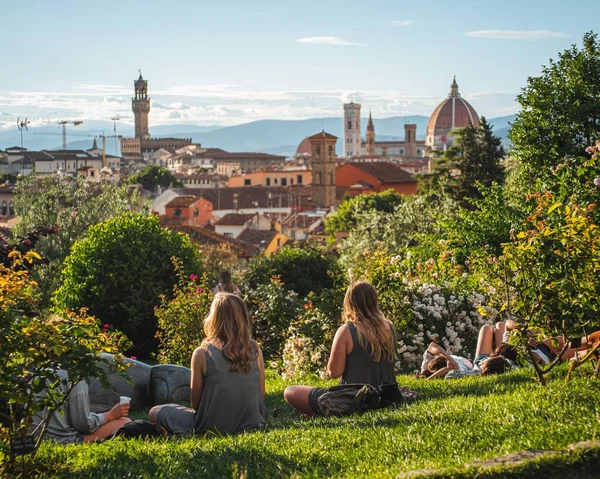 Skupina Přátel Sedících Trávě Krásným Výhledem Florencii Pozadí Jasný Modrý — Stock fotografie