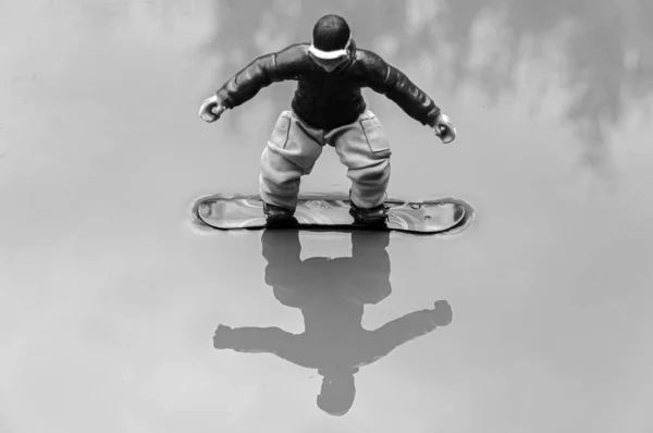 Снимок Оттенках Серого Отражающий Игрушку Сноубордиста Воде — стоковое фото