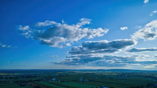 在乌云密布的蓝天下从空中拍摄的田野和房屋 — 图库照片