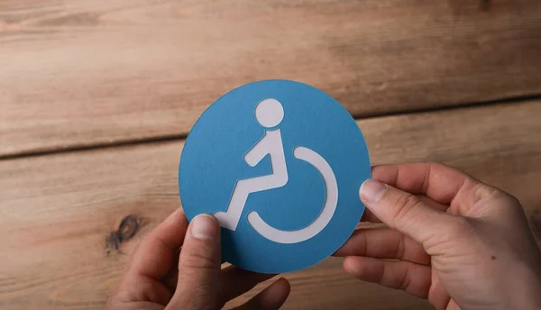 一个拿着蓝色和白色轮椅标志的男人的高角镜头 — 图库照片