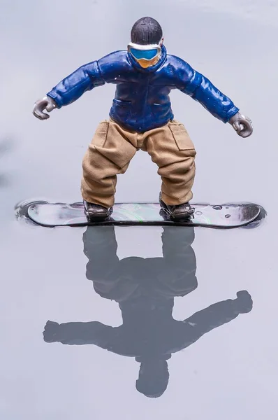 水面上一个塑料雪板人偶玩具的倒影 — 图库照片