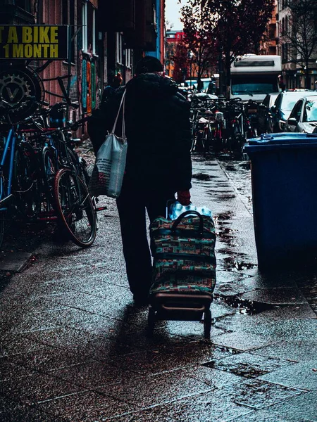 Vertikální Záběr Muže Kráčejícího Chodníku Obklopeného Koly Zaparkovanými Auty Ulici — Stock fotografie