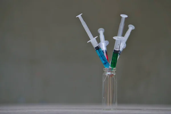灰色の背景を背景にバイアルにカラフルな液体を持つ注射器の閉鎖 — ストック写真