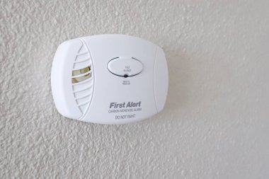SPARKS, NEVADA, UNITED STATES - Apr 27, 2020: A First Alert carbon monoxide detector hangs in a home wall. clipart