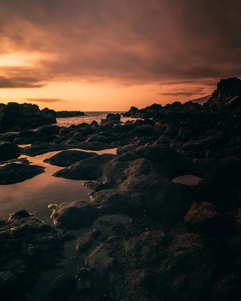 Вертикальный Снимок Скоплений Черной Скалы Пляже Темно Фиолетовым Небом — стоковое фото