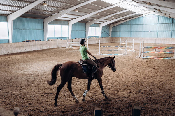 a woman riding a horse in the riding hall