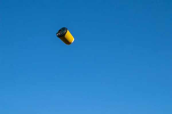 Gegolfd geel papieren kopje voor koffie tegen een blauwe lucht — Stockfoto