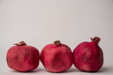Açık arkaplanda kuru kabuklu üç kırmızı nar.