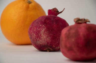 iki kırmızı nar, kuru kabuklu ve bir portakallı.