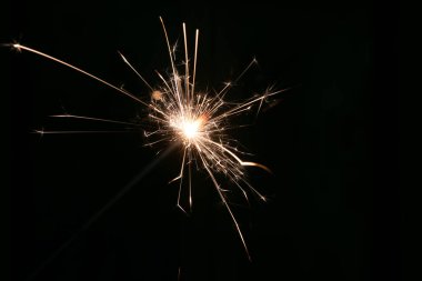 Karanlık bir arka planda yanan bir maytaptan kıvılcımlar
