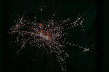 Karanlık bir arka planda yanan bir maytaptan kıvılcımlar