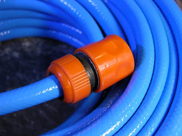 Orange plastic transition connection-nozzle on the watering hose. Close-up, shallow focus.