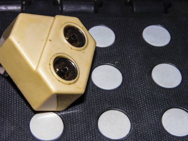 Eski model eski bir robotun dışarı fırlamış gözleri ve sararmış tarih öncesi plastikten yapılmış yüzü gibi, inşaat taburesi üzerine eski model bir ayrıştırıcı. Robot biliminin ötesinde. Yakın çekim, dar odak.