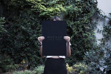 İki eli ve arka planı olan bir pano tutan kadın.