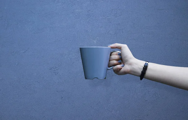 Attrappe einer weiblichen Hand, die eine Kaffeetasse auf isoliertem blauen Hintergrund hält — Stockfoto