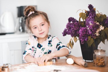 Gülümseyen kız 5-6 yaşlarında. Mutfakta fındıklı kurabiye yapıyor. Kameraya bakıyorum.. 