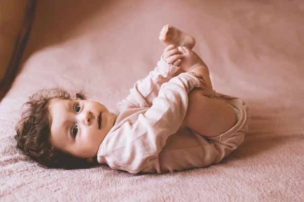 1歳以下のかわいい赤ちゃんは 毛布の上にベッドの上に横たわってピンクのボディスーツを着て カメラを見て幼少期 — ストック写真