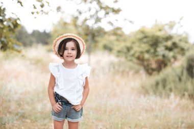 Stylish 3-4 year old wearing casual clothes in meadow. Looking at camera. Childhood. 