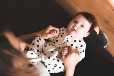 Odada anne eli üzerinde yatan komik bebek. Kameraya bakıyorum. Üst Manzara. Çocukluk. 